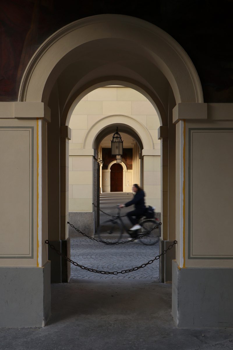 Fahrradfahrerin zwischen den Arkadengängen im Hofgarten in München