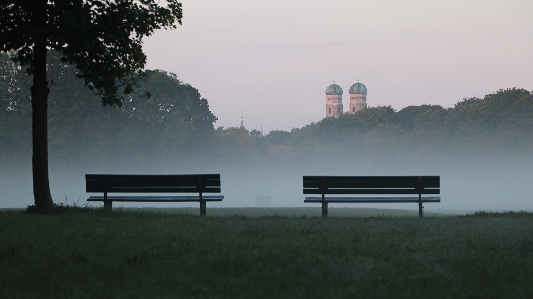 Morgens im Englischen Garten in München mit Blick auf die Frauenkirche bei Nebel